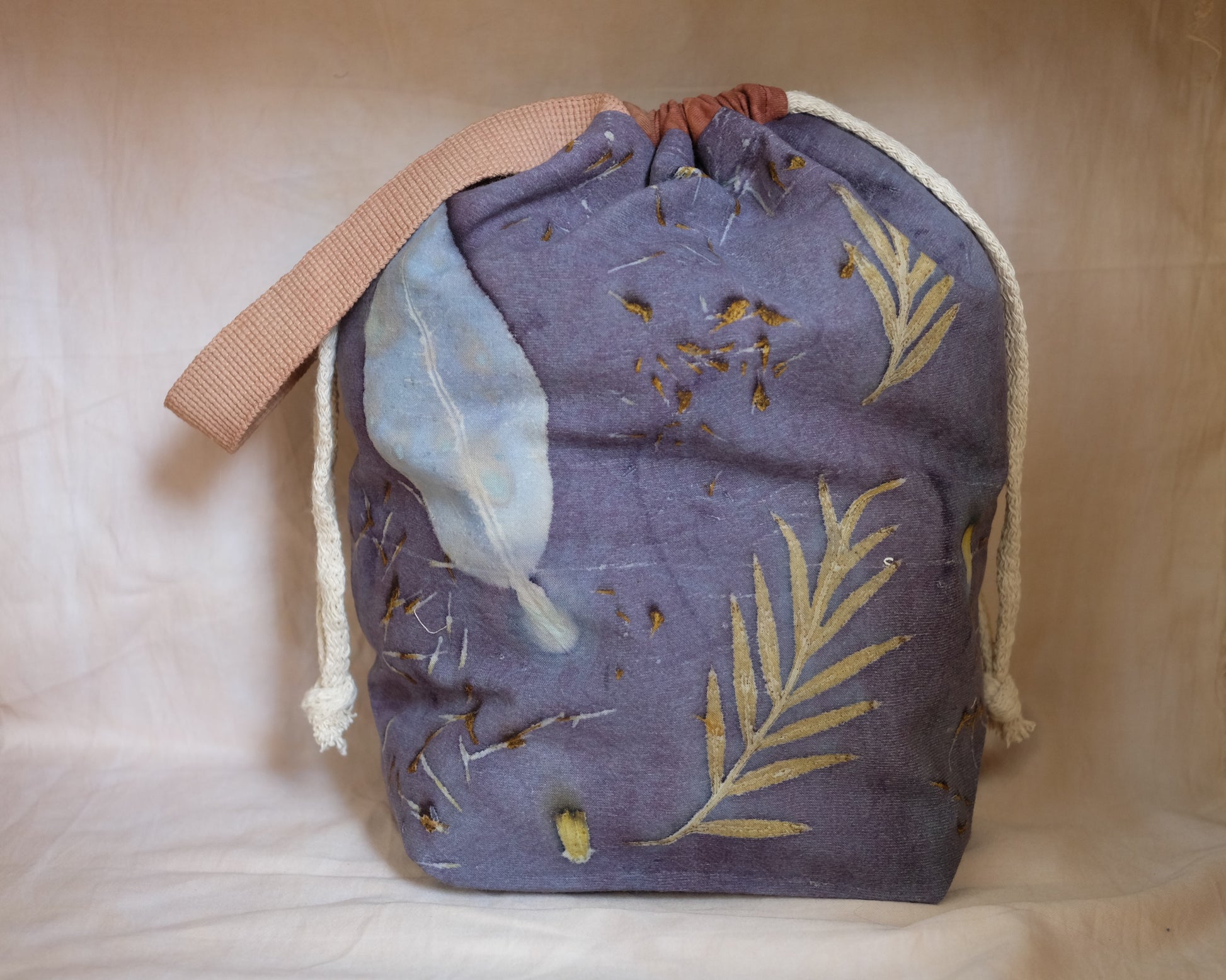 Handmade eco-printed drawstring project bag with botanical leaf prints on natural cotton fabric, featuring a drawstring closure and handle.