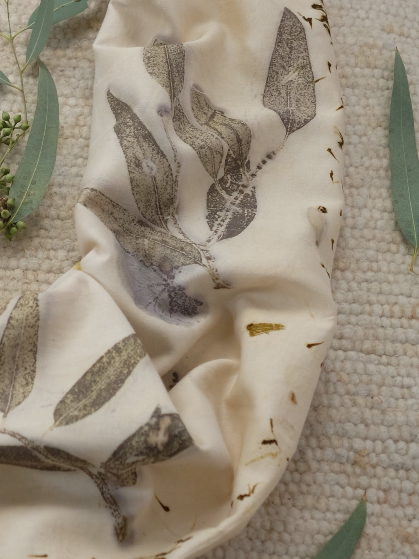 section of an ecoprinted scarf with leaved of eucalyptus and marigolds.