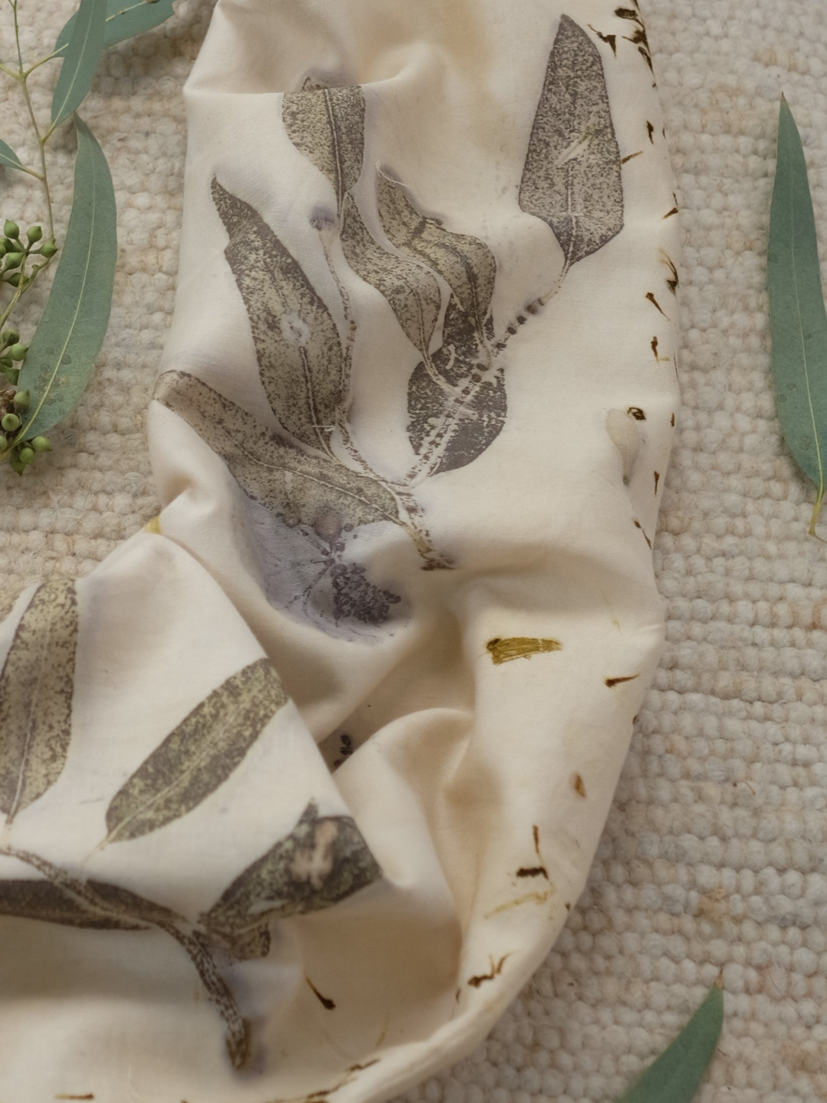 section of an ecoprinted scarf with leaved of eucalyptus and marigolds.