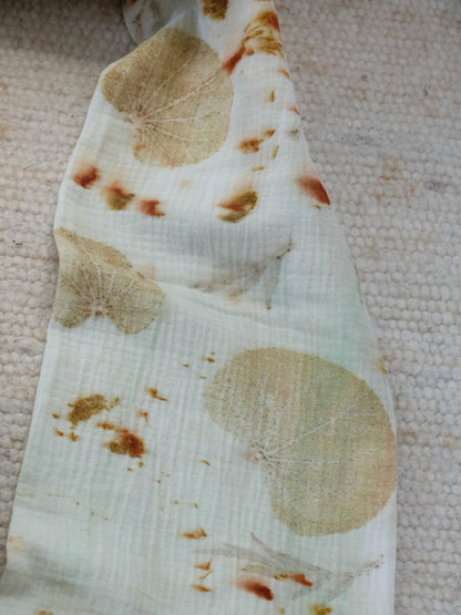 section of an ecoprinted scarf, in creme color and yellow leaves. with speckles of orange.