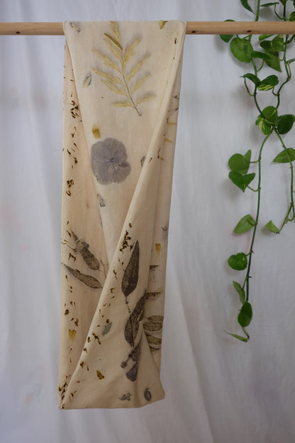 ecoprinted scarf, with leaves of eucalyptus and geranioum. pictured he folded side of the infinity scarf that is hanging on a dowel.