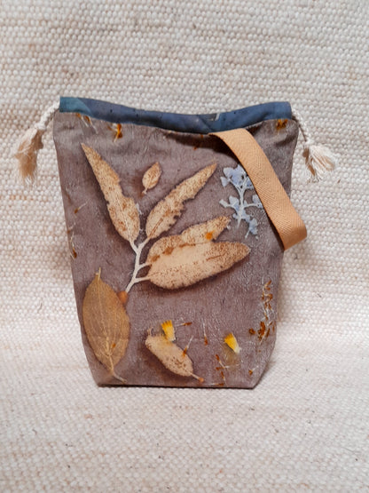 hand make project bag, with ecoprinted fabric. varius leaves in a grey/purple background.